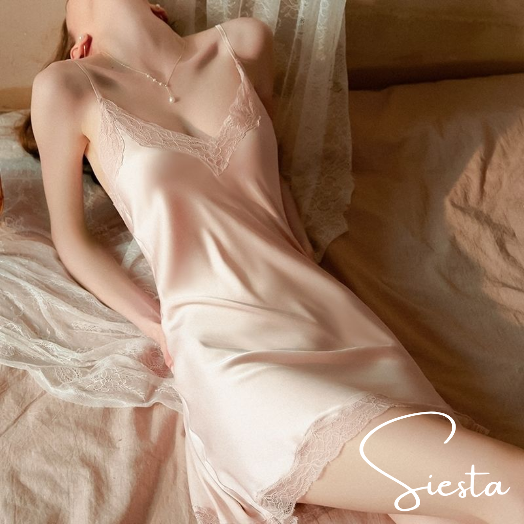 Woman wearing a pink lace nightgown on a bed with 'Siesta' branding.
