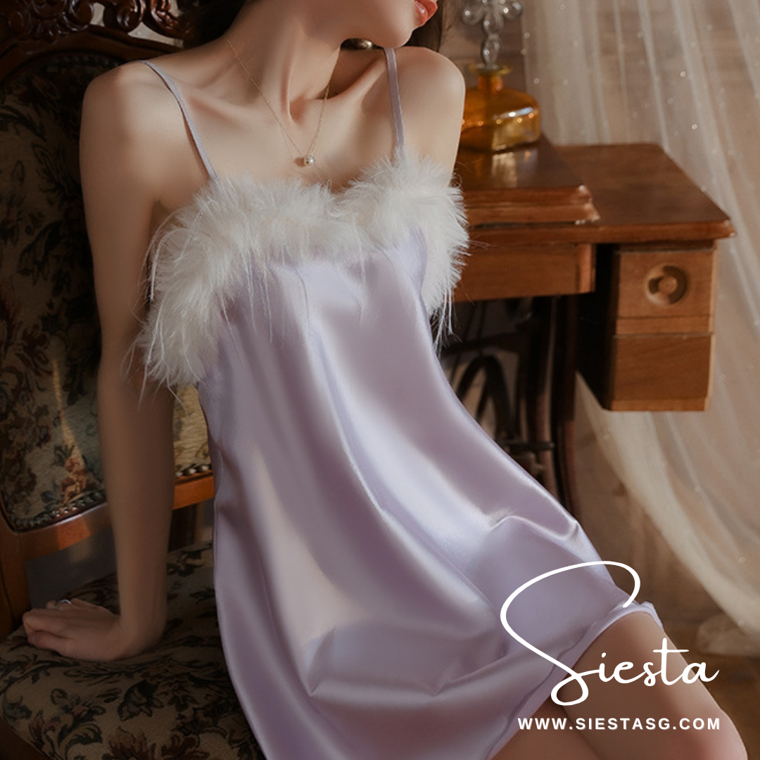 Woman wearing a white satin nightgown with feather details in a vintage room.